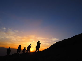 Silhouette people standing on mountain against sky during sunset