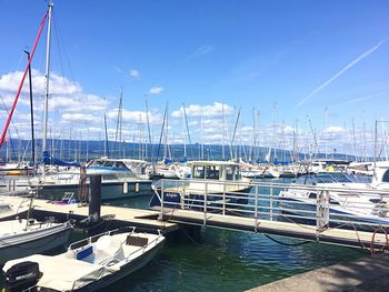 Boats moored at harbor against blue sky
