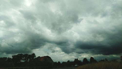 Scenic view of trees on field against storm clouds