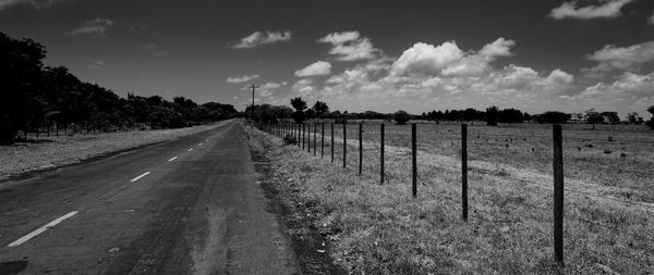 Road amidst field against sky