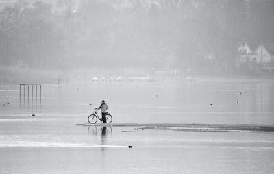 Side view of man riding bicycle at beach