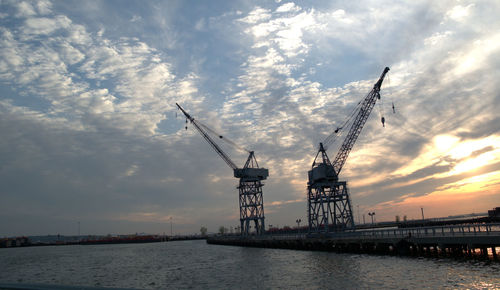 Crane against cloudy sky at sunset