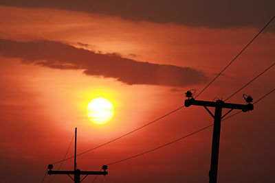Low angle view of silhouette electricity pylon against sky during sunset