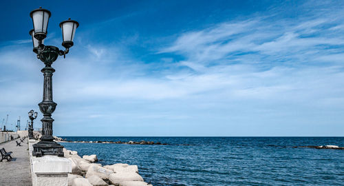Street light by sea against sky
