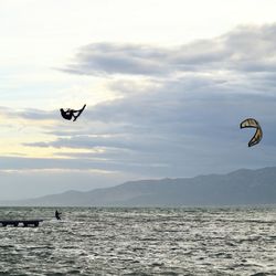 Man kitesurfing over sea against sky
