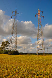 Low angle view of electricity pylon on field against sky