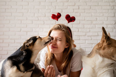 Lovely pet. young woman with her cute mixed breed dog at home having fun and kissing, funny picture