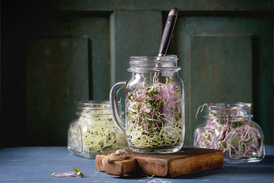 Close-up of bean sprouts in jars on table against door