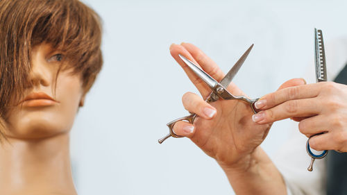 Hand of a hairdresser holding hairdressing scissors, explaining students haircutting techniques 