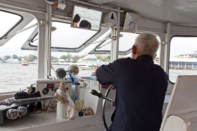 Rear view of man standing on boat in sea