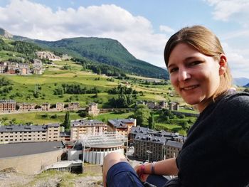 Portrait of smiling young woman sitting against mountain