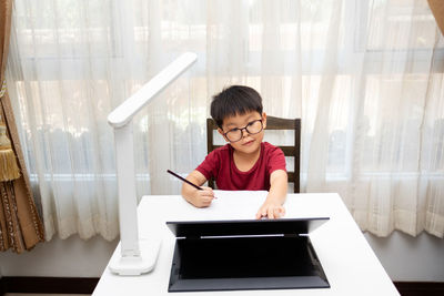 Portrait of boy with mobile phone while standing on table