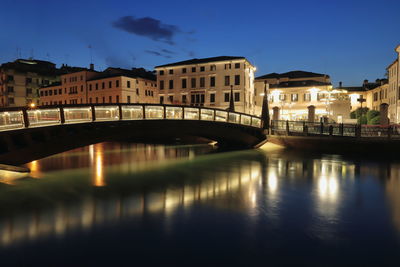 Bridge over river by buildings against sky in city