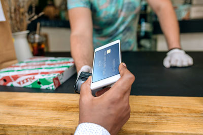 Man making contactless payment through smart phone at restaurant