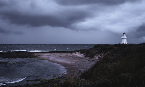 Lighthouse by sea against sky