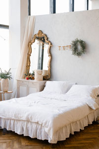 A double bed with white linens and pillows in the bedroom decorated for christmas and new year.