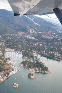 Cropped airplane flying over sea by mountain