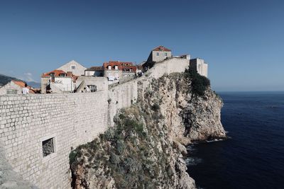 Building by sea against clear blue sky