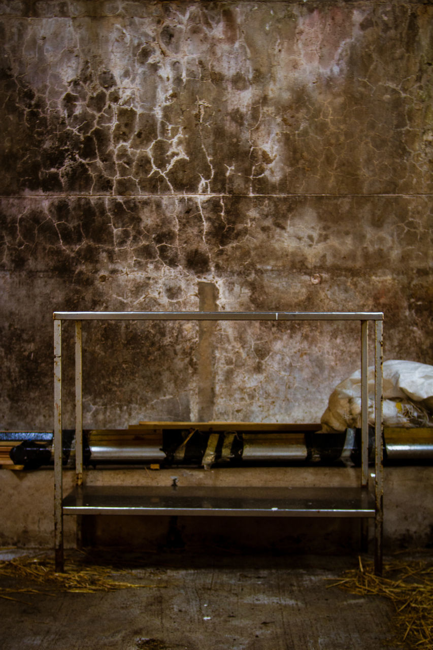 EMPTY BENCH AGAINST WALL IN ROOM