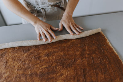 High angle view of woman's hands rolling dough
