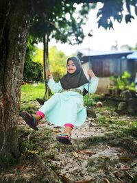 Cute girl swinging against tree