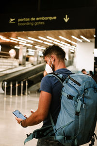 Man wearing mobile phone while wearing mask at airport