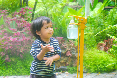 Cute boy standing against plants