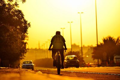 Rear view of man on street against sky during sunset