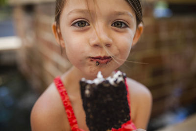 Portrait of happy girl eating chocolate popsicle