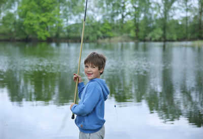Portrait of smiling boy fishing on lake