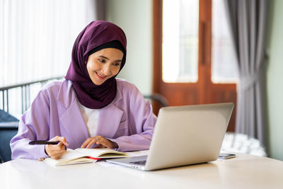 Young woman using laptop at table