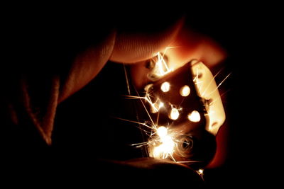 Close-up of man holding illuminated candle