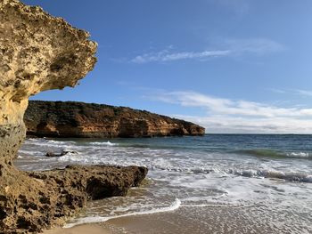 Rock formation on beach against sky