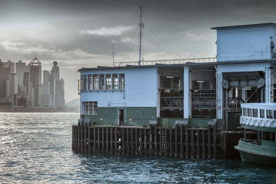 Buildings by river against sky in city