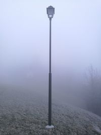 Street light on field against sky during foggi winter