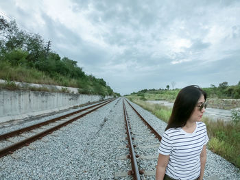 Woman standing on railroad track against sky