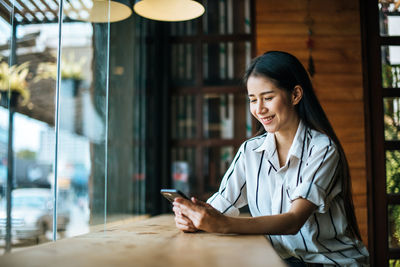 Woman using phone while sitting on table