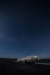 Damaged airplane on field against sky at night