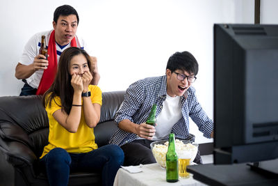 Friends cheering while watching soccer on tv