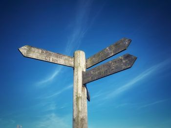 Low angle view of cross on wooden post against sky