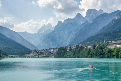 Scenic view of lake by mountains against cloudy sky