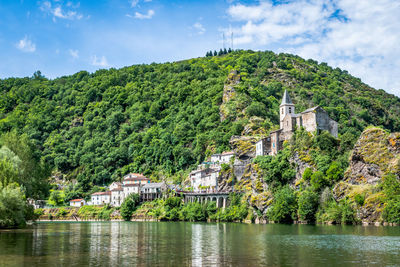 Scenic view of river by buildings against sky