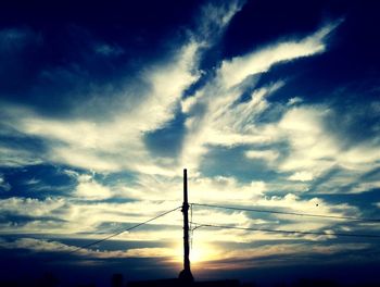 Low angle view of silhouette electricity pylon against sky