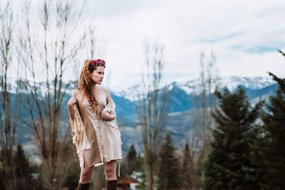 Young woman standing against trees and plants