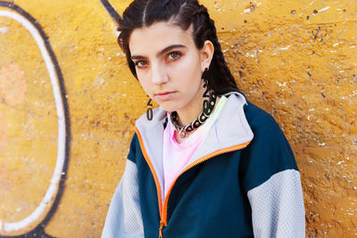 Portrait of young woman standing against yellow wall