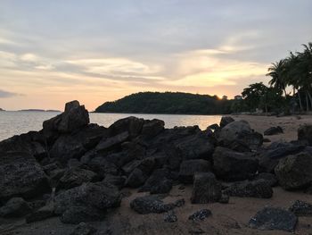Rocks on beach against sky during sunset
