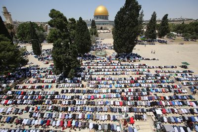 High angle view of crowd praying on field during sunny day