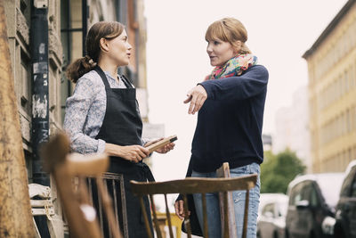 Customer pointing while having communication with owner outside antique shop