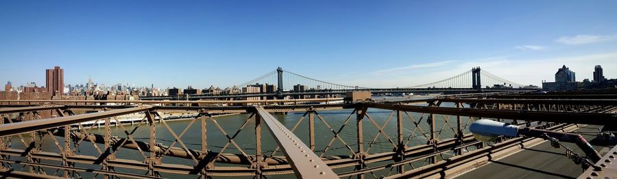 Panoramic view of manhattan bridge over east river against sky seen from brooklyn bridge