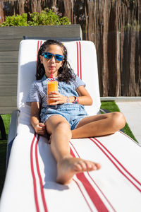 Little girl drinking orange juice on a hammock
